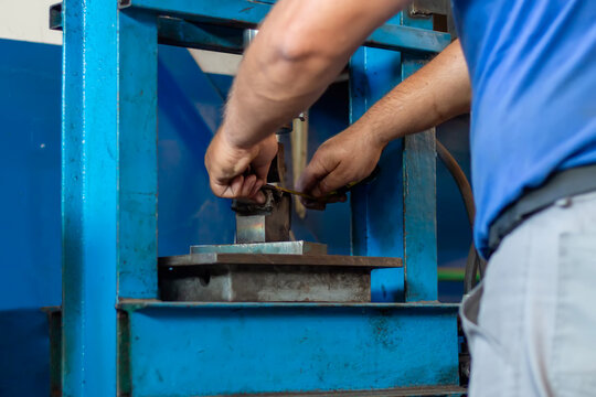 Car mechanic working on a hydraulic floor press in a workshop. Durable hydraulic press designed for efficient metal forming and shaping