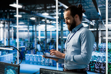 Programmer working in server farm with hardware supporting advanced analytics tasks and data mining. Data center IT expert doing maintenance on racks storing blockchain records