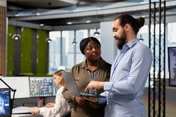 Teamworking programmers collaborating at work to train deep learning models for anomaly detection automation. IT staff members working together, using AI on PC in office to repair network issues