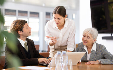 three office workers are sitting at table animatedly and actively discussing work