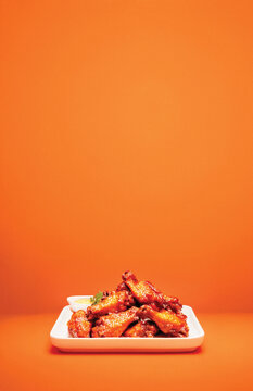 Hot Wings on White Plate and Orange Background With Copy Space