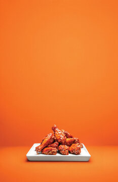 Hot Wings on White Plate and Orange Background With Copy Space