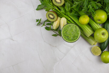 Fresh green smoothie with fruits and vegetables on marble table top view with copy space