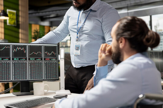 Manager overseeing work of risk analyst using trading platform to review stock exchange shares prices. Team leader and prop firm employee analyze portfolio reports, checking for financial risks - Powered by Adobe