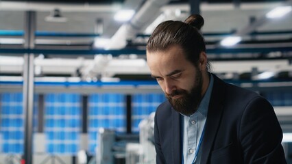 Facility supervisor in a suit monitoring solar panel assembly line, reflecting professional occupation and executive level involvement in renewable energy growth. Sustainability. Camera B.