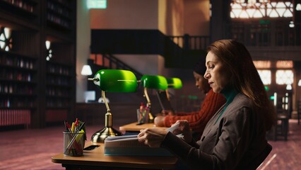 Public library setting with older woman studying under soft lighting, surrounded by books and academic materials. Person representing dedication for the journey toward university degree.