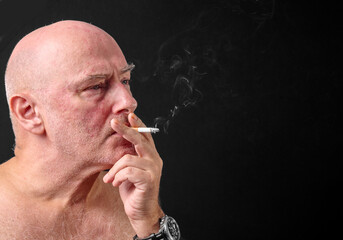 Fototapeta premium Middle aged man smoking a cigarette,as thick unhealthy smoke flows from his mouth,England,United Kingdom.