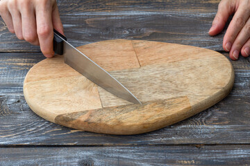 Cutting board with chef knife and hands on rustic wooden kitchen table