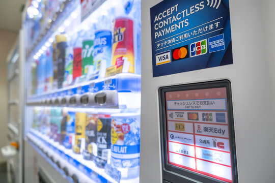 Contactless payment option logos, including Visa, Mastercard, JCB, and mobile wallet, on a Japanese vending machine. Concept of cashless society, convenience technology, and urban automated retail 