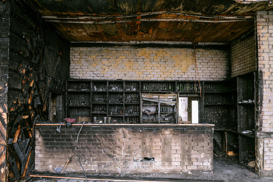 Charred wooden bar. Shelves with drinks after fire.