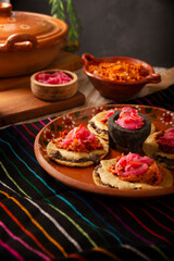 Panuchos, a typical dish from Yucatan, Mexico. A handmade, fried corn tortilla filled with beans, topped with cochinita pibil, pickled red onion, and habanero pepper.