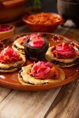 Panuchos, a typical dish from Yucatan, Mexico. A handmade, fried corn tortilla filled with beans, topped with cochinita pibil, pickled red onion, and habanero pepper.