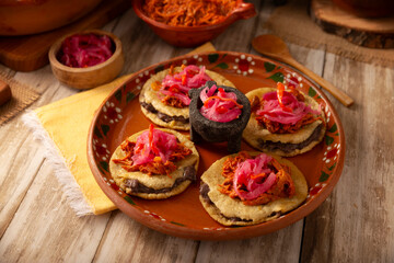 Panuchos, a typical dish from Yucatan, Mexico. A handmade, fried corn tortilla filled with beans, topped with cochinita pibil, pickled red onion, and habanero pepper.