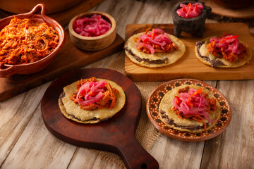 Panuchos, a typical dish from Yucatan, Mexico. A handmade, fried corn tortilla filled with beans, topped with cochinita pibil, pickled red onion, and habanero pepper.