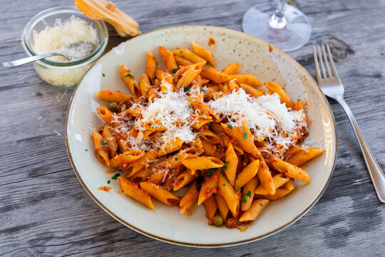 Italian pasta pene rigate with minced meat and herbs in tomato sauce served on platter