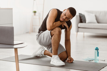 Fototapeta premium Fitness Burnout. Exhausted African American Guy Tired Of Online Workout Exercising At Laptop Sitting On Floor At Home. Beginner Resting After Difficult Exercise Concept. Selective Focus