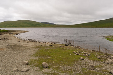 A lake with a rocky shoreline and a cloudy sky in the background