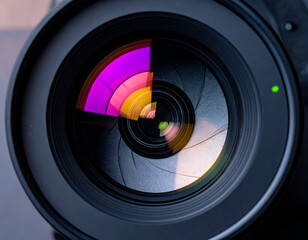 Detailed view of a modern camera lens showing the aperture mechanism and colorful light reflections. Perfect for photography, technology, and art themes.