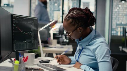 Equity analyst in prop firm office reviews quarterly earnings to assess future stock market value, taking notes. Trader conducts financial analysis to improve investments, writing down info, camera B - Powered by Adobe