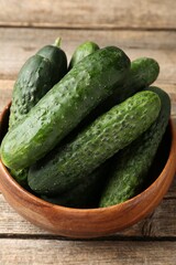 Fresh cucumbers in bowl on wooden table, closeup