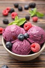 Delicious sorbet with fresh berries and mint in bowl on wooden table, closeup