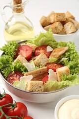 Delicious salad with croutons and ingredients on white wooden table, closeup