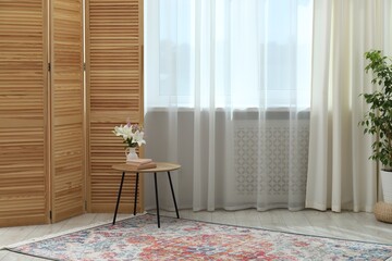 Stylish furniture and houseplant near window with curtains in living room. Interior design