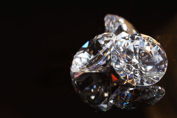 Shiny diamonds on mirror surface against black background, closeup. Space for text