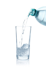 Pouring refreshing soda water from bottle into glass on white background