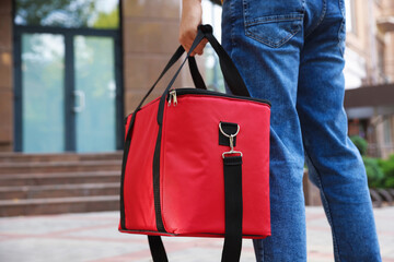 Courier with thermo bag on city street, closeup. Food delivery service