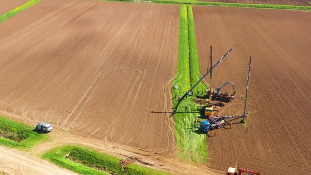Workers install high voltage line support using construction equipment and a crane. Power line support installation.