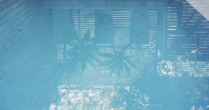 Drifting pink donut-shaped inflatable ring in home pool water, near table holding folded towels