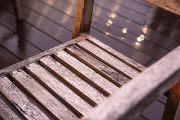 Close-up of a rustic wooden chair with light reflections on the wet floor