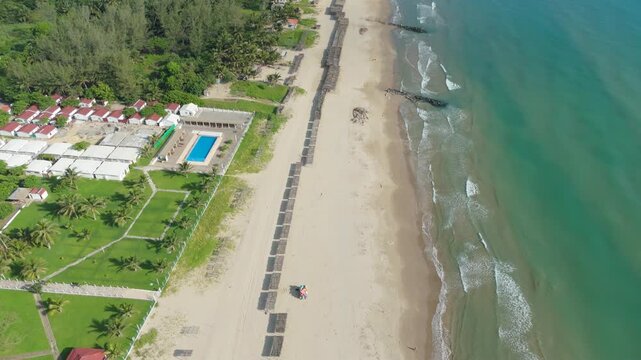 Aerial parallel tracking along beachfront with pool, sandy beach and palm-lined coast in Tuxpan, Veracruz, Mexico, 4K