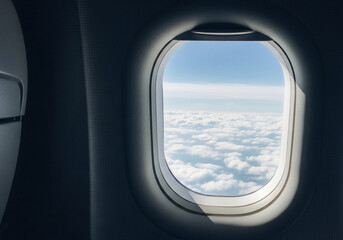 View from airplane window above fluffy white clouds and blue sky