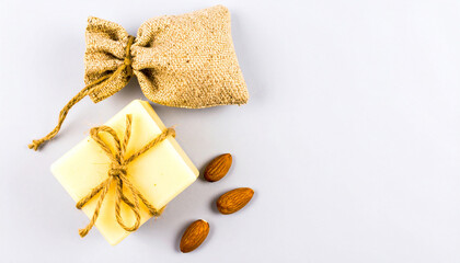 Natural Soap Delight: A close-up shot of handcrafted soap paired with a small, textured sack tied with natural twine, accompanied by a handful of almonds, a testament to simple, pure beauty.