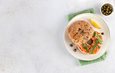 Bagel with salmon, cream cheese, cucumber and arugula. Top view. Copy space
