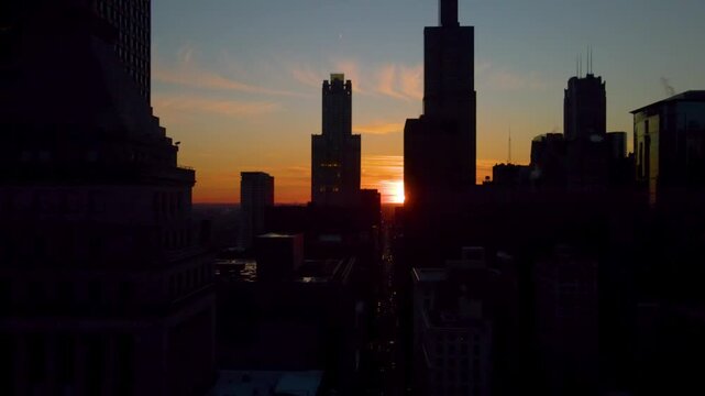 Drone shot of Chicago Henge sunset with the sun aligned behind the skyline silhouette, glowing against a deep blue and orange sky over the city.
