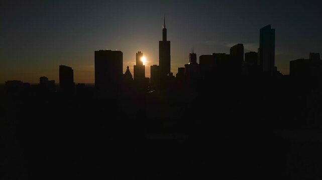 Drone shot of Chicago Henge sunset with the sun aligned behind the skyline silhouette, glowing against a deep blue and orange sky over the city.