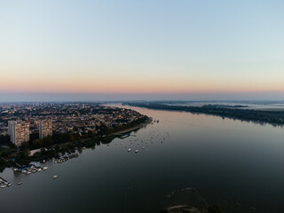 Aerial sunrise view over Belgrade city, river bend and urban skyline at golden light. g.