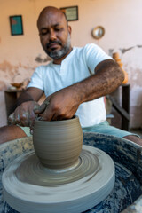 Afro-Brazilian man, third generation of a family of potters, crafting clay pieces inspired by ancient Tapajonic art to preserve cultural tradition in Santarem, Para, Brazil