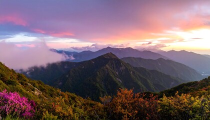 A breathtaking vista of a mountain range at sunset, displaying a vibrant color palette of purples, pinks, and oranges, with layers of mountains and clouds.