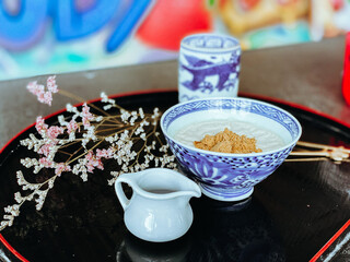 A hand is pouring rich, sweet sauce over a delicious Japanese dessert. The glossy sauce slowly drizzles and coats the surface of the treat, adding a fragrant sweetness and an irresistible glossy finis