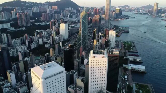 An elevated, slightly blurred perspective of a sprawling modern metropolis with towering skyscrapers and a vast harbor during a hazy, golden hour.