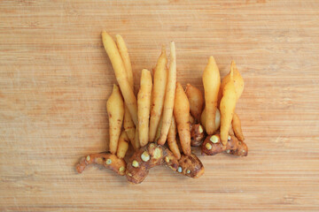 Finger root or Chinese ginger on bamboo wooden background, preparation process for cooking. Top view.