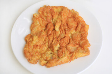 Deep fried omelet in white plate against white background.