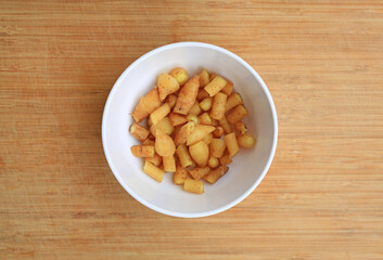 Chopped finger root or Chinese ginger in white bowl against wooden background, preparation process for cooking. Top view.