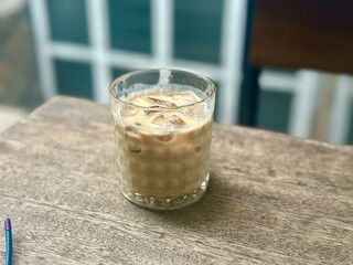 Cold latte served with ice cubes in a transparent glass, popular coffee beverage. Bandung, Indonesia - August 15, 2025