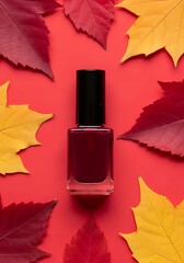 Autumn beauty concept dark red nail polish bottle surrounded by vibrant fall leaves on a red surface