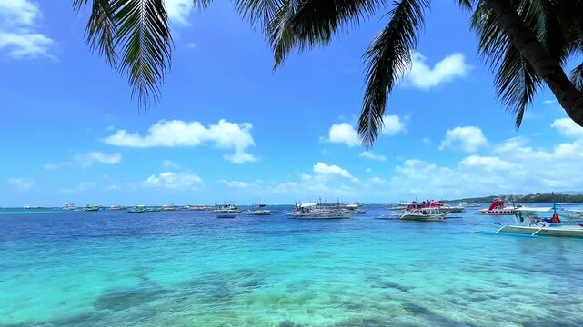 Adventure parasailing boats anchored in stunning turquoise ocean, framed by palm trees under bright blue skies &mdash; ideal for travel, tourism, and water sports projects.